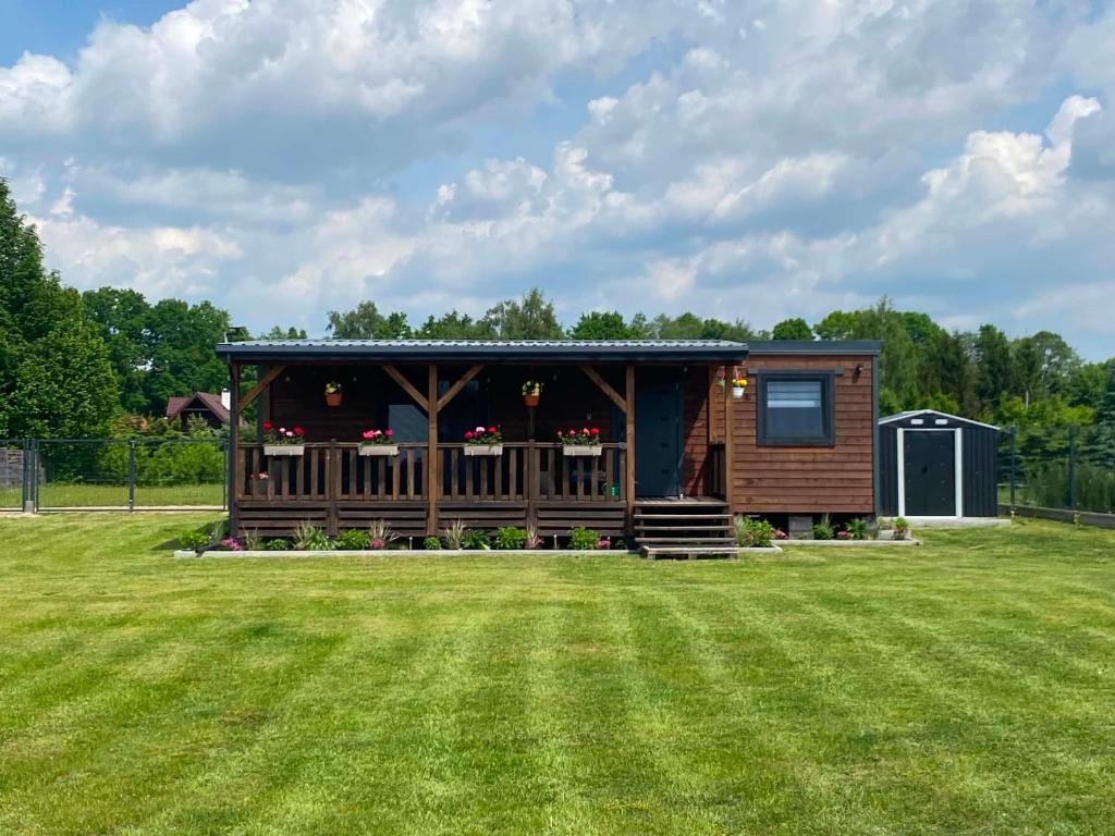 a small cabin with a large grass yard at Winiec Mobile Home in Miłomłyn