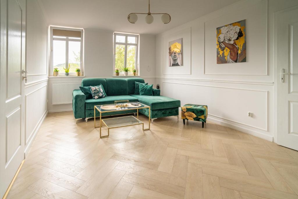 a living room with a green couch and a table at Apartament nad bulwarem in Lidzbark Warmiński