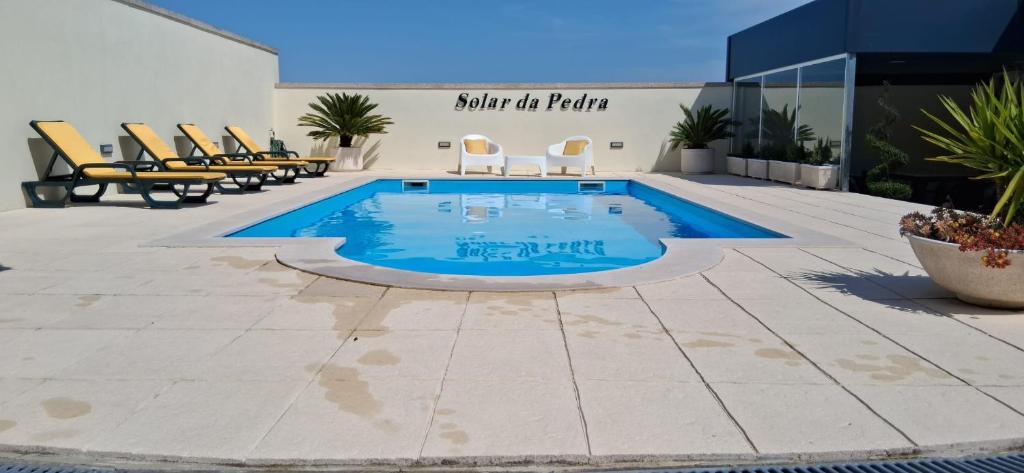a swimming pool on a patio with chairs around it at Solar da Pedra in Paços de Ferreira