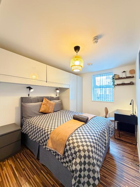 a bedroom with a bed with a checkered blanket at Britlodge Ruskin Stay in Manchester