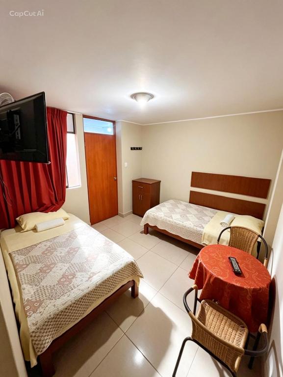 a room with two beds and a table and a tv at Hospedaje Valencia in Ica