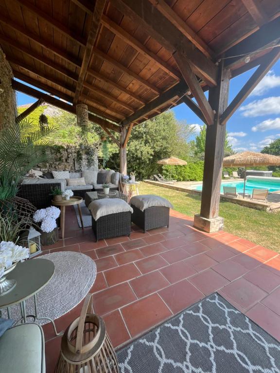 a patio with tables and chairs under a wooden pergola at Gites Boutique in Villamblard