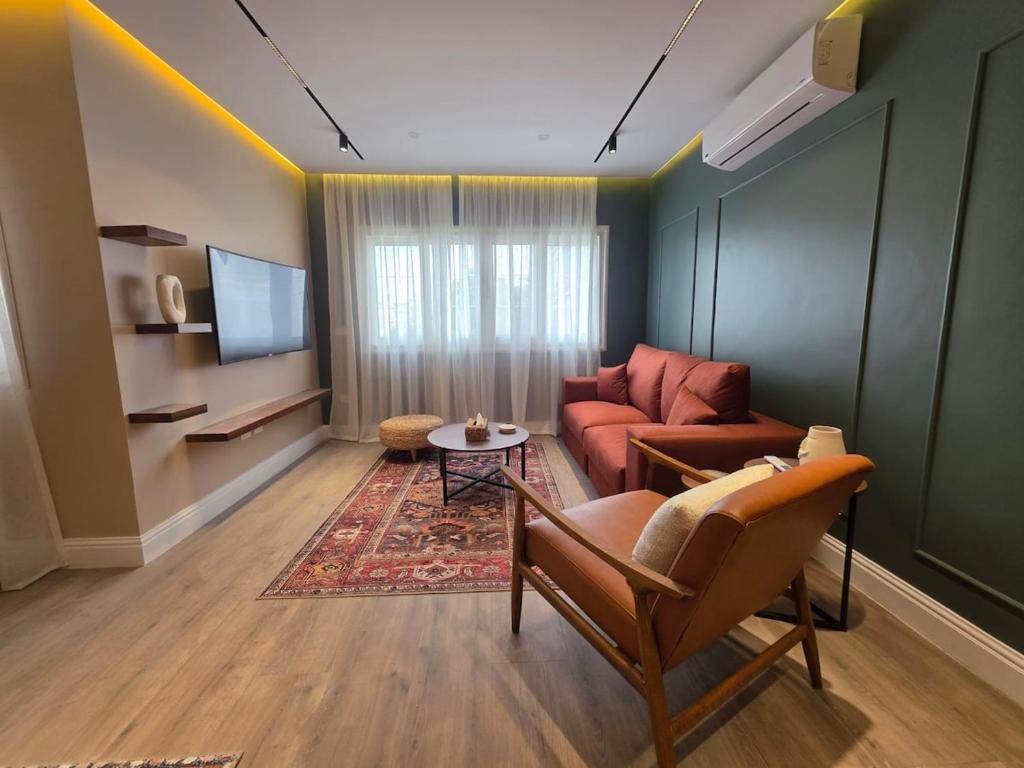 a living room with a couch and a tv at Boho Chic 2BR Retreat Mountain View Executive in New cairo