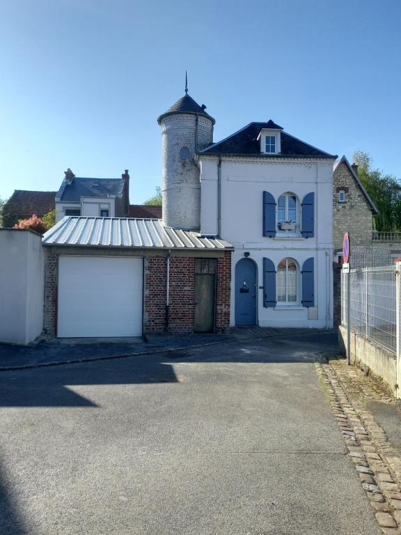 a white house with a gate and a garage at La petite Tourelle Ruelle de la Fontaine in Péronne