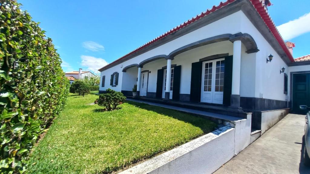 a house with a green lawn in front of it at Casa Pascoal in Ribeira Grande