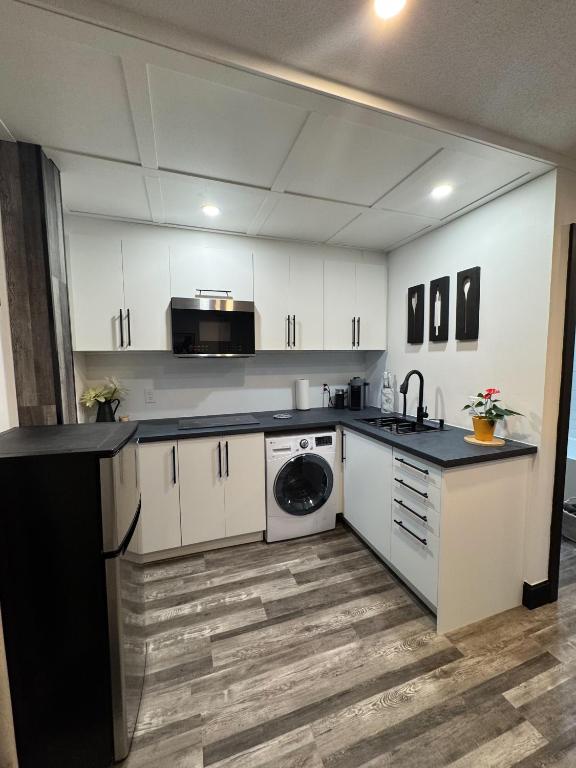 a kitchen with white cabinets and a washing machine at Studio Moderne Chic Gatineau Ottawa in Gatineau