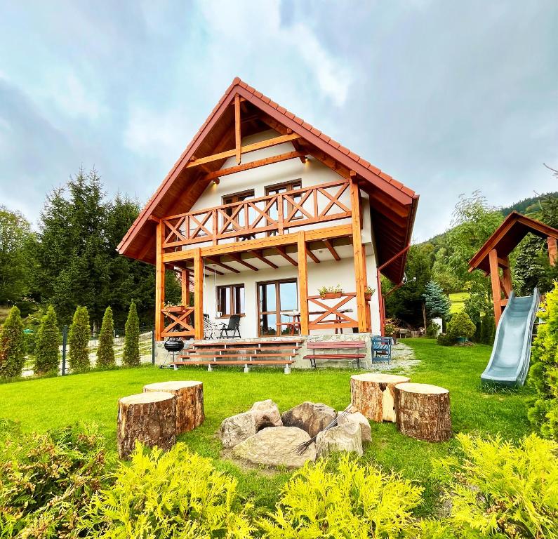 a log house with a slide in the yard at Alpejka - Domki w górach in Idzików