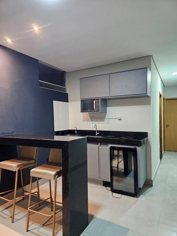 a kitchen with a black counter and some chairs at D Castro Executive in Montes Claros
