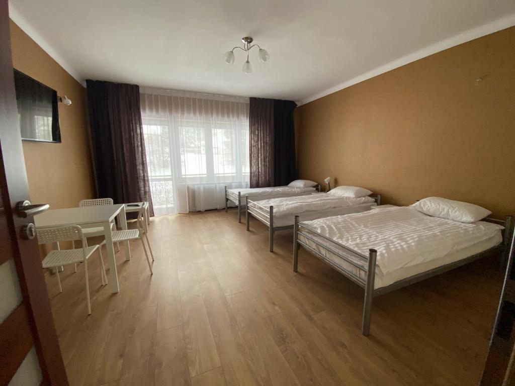 a room with three beds and a table and chairs at Noclegi lebudbis in Wąchock