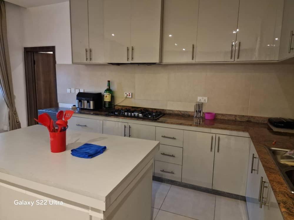 a kitchen with white cabinets and a red cup on a counter at Nest Nova in Alagbado