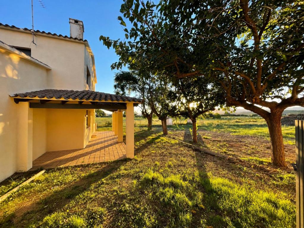 a building with a porch and trees in a field at La Sènia in Miravet