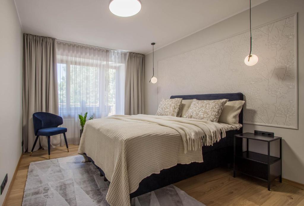 a bedroom with a large bed and a blue chair at Uus Street Apartment, Modern Stay near City Centre with Free Parking in Tartu