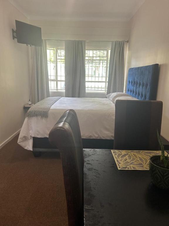 a bedroom with a large bed and a blue chair at Dee's 2 BR guest flat in Ladybrand in Ladybrand