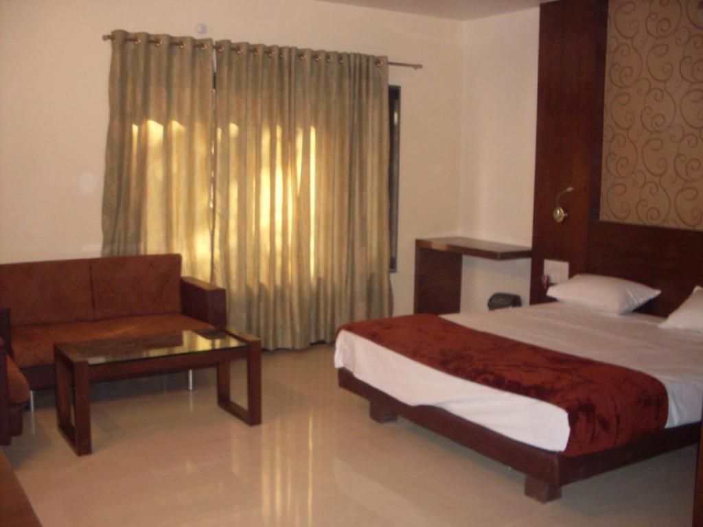 a bedroom with a bed and a couch and a table at New Hotel Shree Ganga in Shājāpur