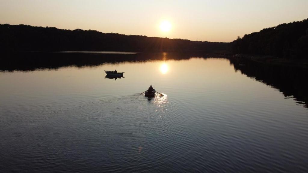 two people in boats on a lake at sunset at Pokoje u Niny in Nowe Rumunki