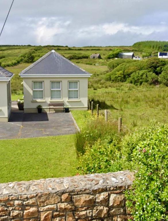 a house in a field with a stone wall at Fairy Fort View, Lahinch in Carrowauff