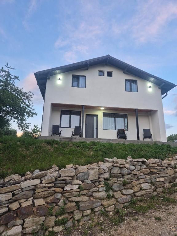 a large white house with a stone wall at Casa LSA in Arefu