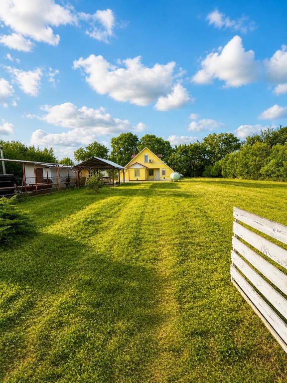 a field with a house and a white fence at Peresi paradicsom in Mezőtúr