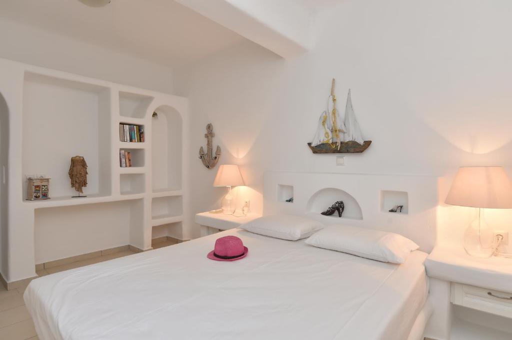 a white bedroom with a white bed with a pink hat on it at Yria Holiday Home Paros in Márpissa