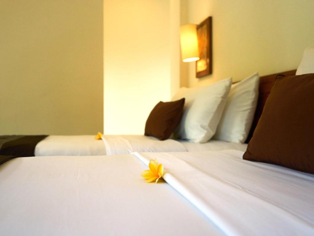 Dos camas en una habitación de hotel con una flor. en Eden House Ubud en Ubud