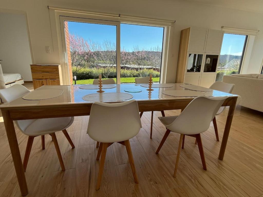 a dining room table with white chairs and a large window at maison bois in La Forest-Landerneau