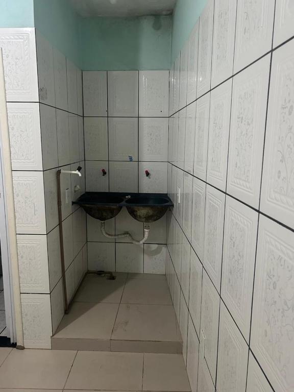 a bathroom with a sink and a tiled wall at Humilde House in Itabuna