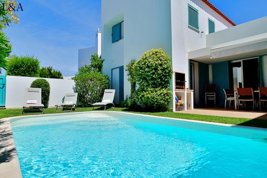 a swimming pool in front of a house at L&A Villa Prainha 3 Bedrooms Heated Pool 5 m walking to the beach in Alvor