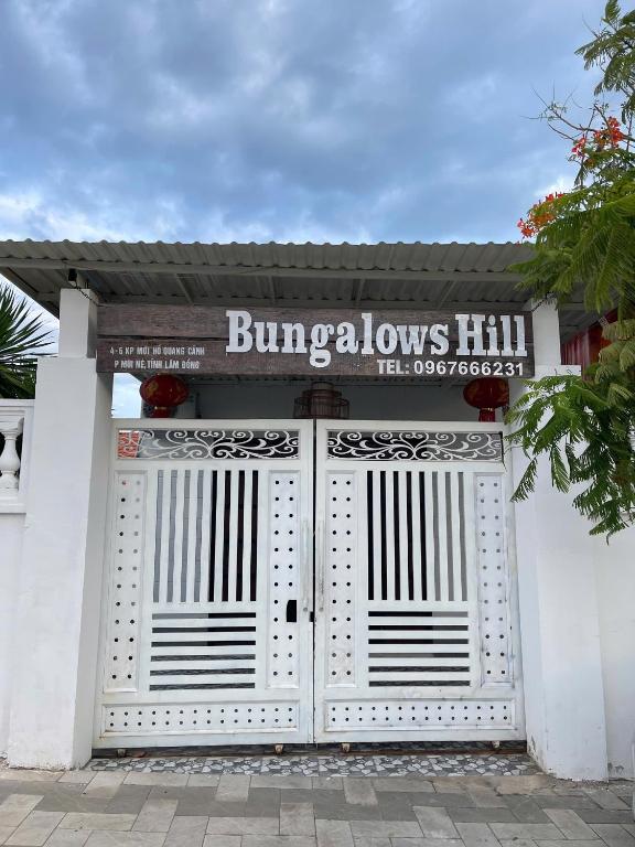 a white building with a gate with a sign on it at Bungalows Hill Mũi Né in Ấp Thiện Long