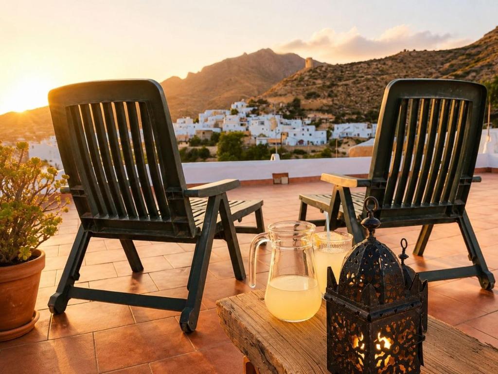 two black chairs sitting on a table with orange juice at Refugio rural en Níjar con jardín privado barbacoa y solarium con vistas únicas in Níjar