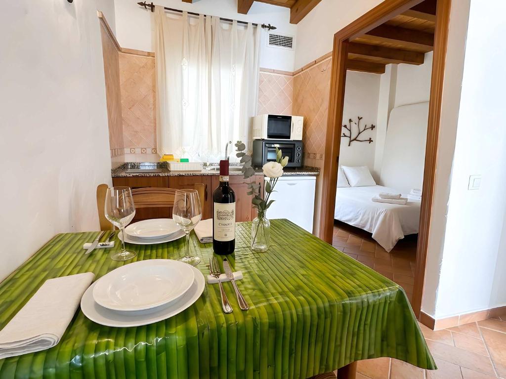 Una mesa verde con una botella de vino y copas. en Apartamento Cerca del Mar con Azotea Compartida, en Conil de la Frontera