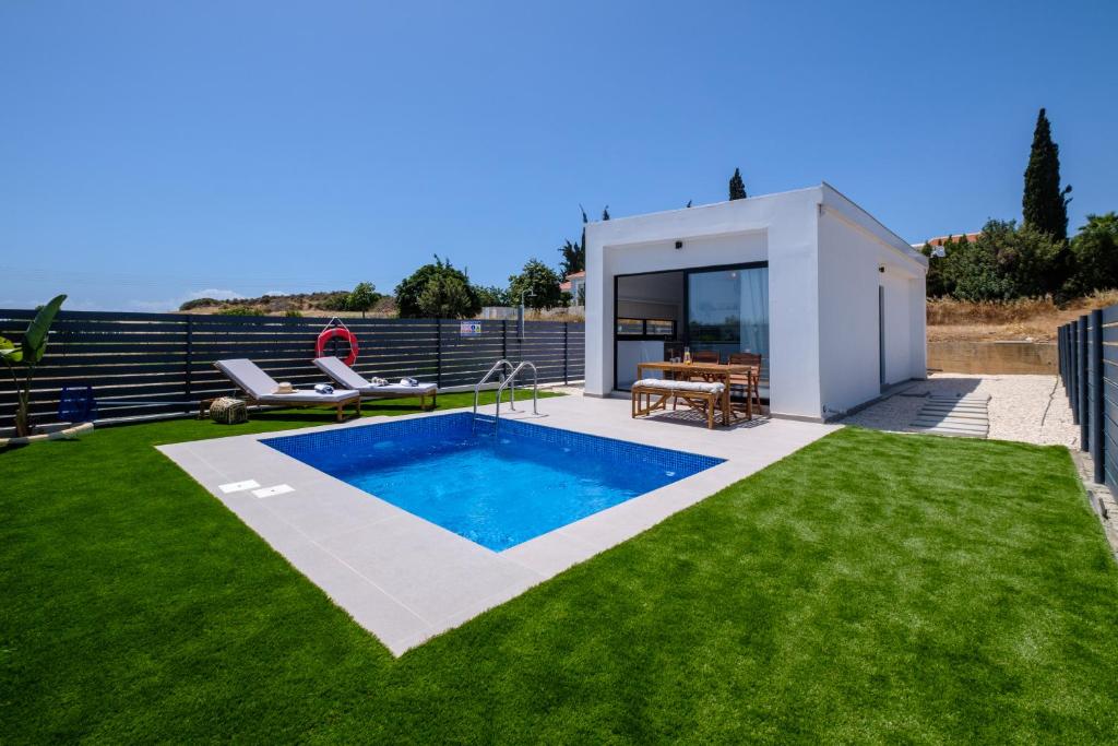 a backyard with a swimming pool and a house at Sea Breeze Studios in Pervolia