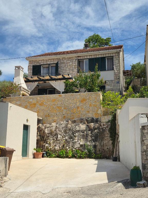 a house with a stone wall and a building at Apartman NONO in Splitska
