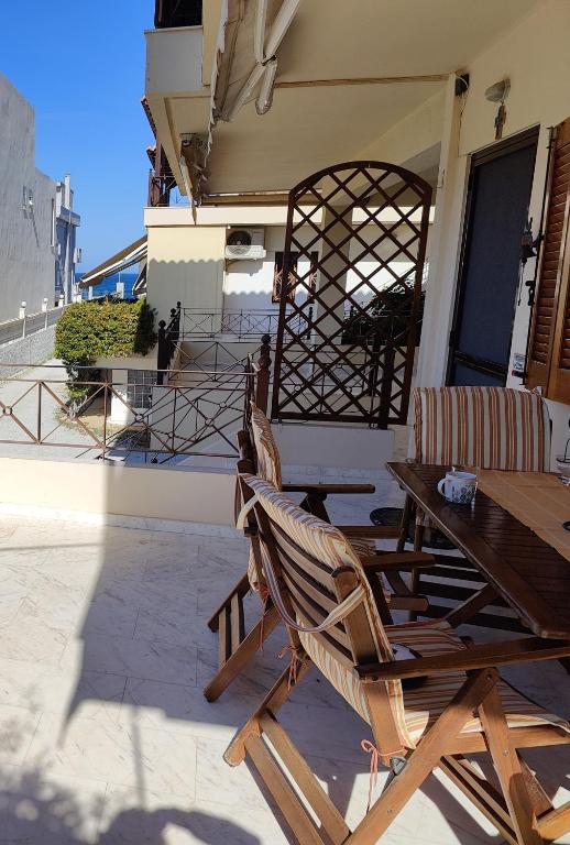 two chairs and a wooden table on a patio at Two-floor house next to sea in Loutraki