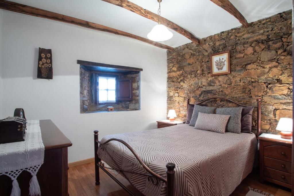 a bedroom with a bed and a stone wall at Casa do Dão in Oleiros