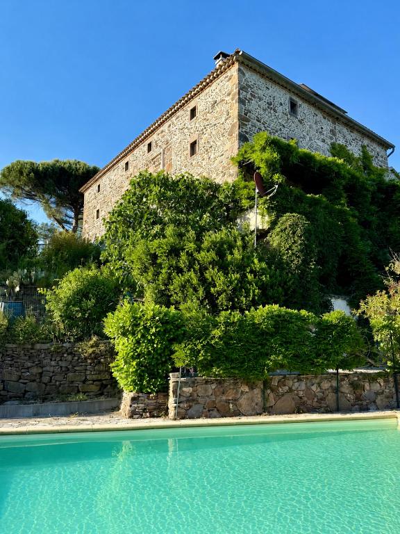 an old building with a swimming pool in front of it at Mas du pommier Gala in Gagnières