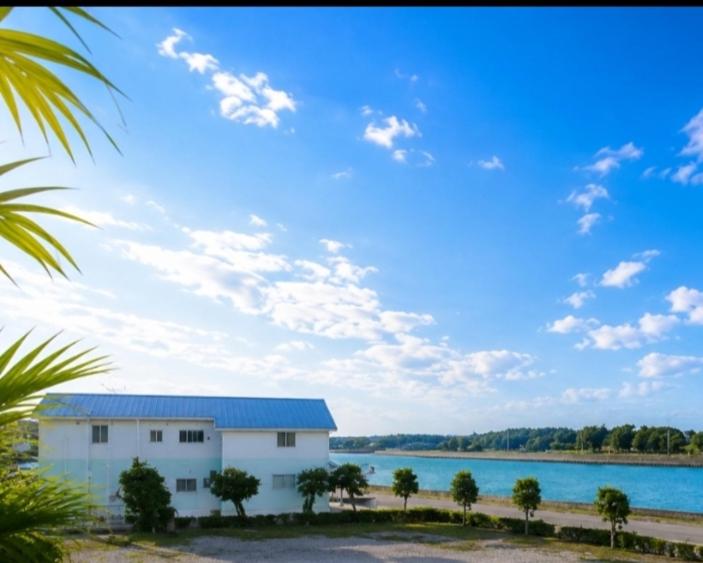a white building next to a large body of water at ほぬのいえ Honu's house in Uruma