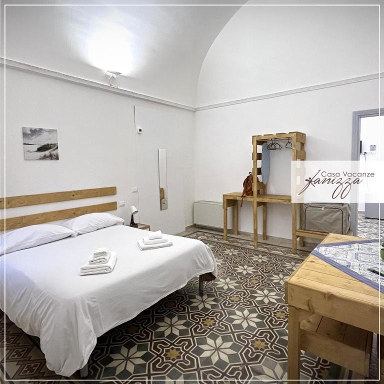 a bedroom with a white bed and a table at Rebecca e Sofia Stone House affittacamere in Alberobello
