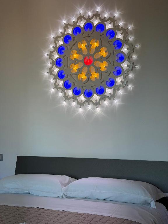 a chandelier hanging over a bed with a white bed sidx sidx at Lu Sule lu Mare le Luci in Scorrano