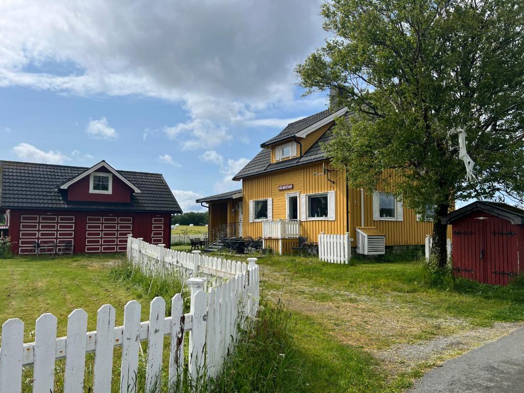 a yellow house with a white fence and a barn at Huset Heimstad i Herfjord in Skippervik