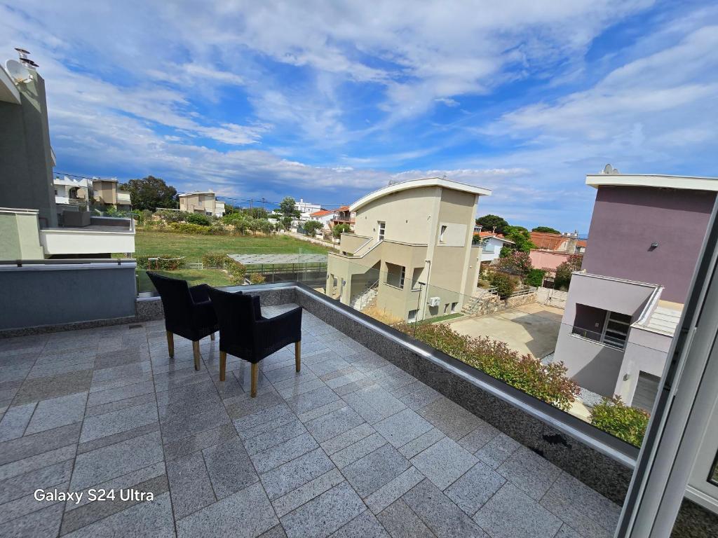 a balcony with two chairs and a view of a city at Angelo Apartments in Paralía Avdhíron