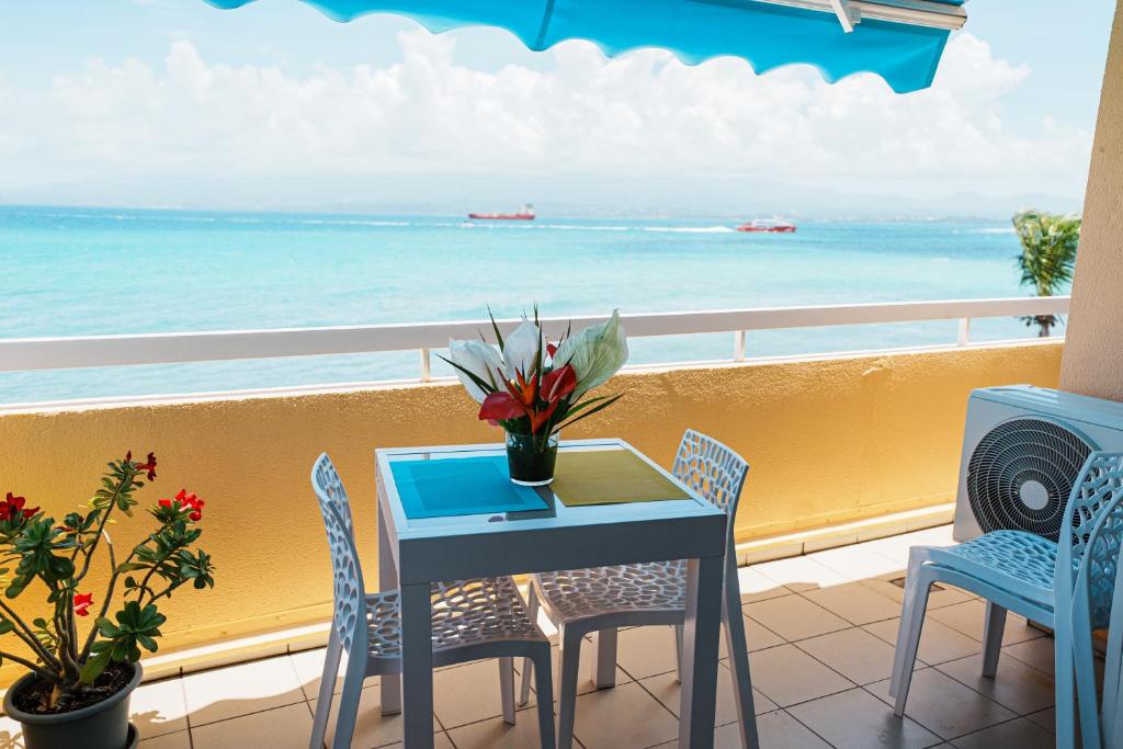 a table and chairs on a balcony with the ocean at La Perle Fleur d'Epée in Le Gosier