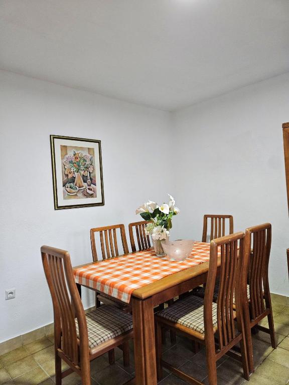 a dining room table with four chairs and a table and a vase of flowers at Vikendica Tobi in Čapljina