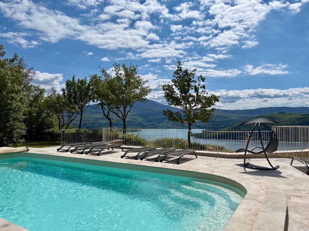 a swimming pool with lounge chairs and a view of the water at Domaine de la Ferme Para Lou in Sainte-Croix-de-Verdon