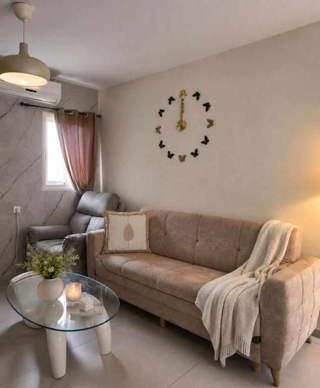 a living room with a couch and a clock on the wall at Coastal Comfort in Haifa