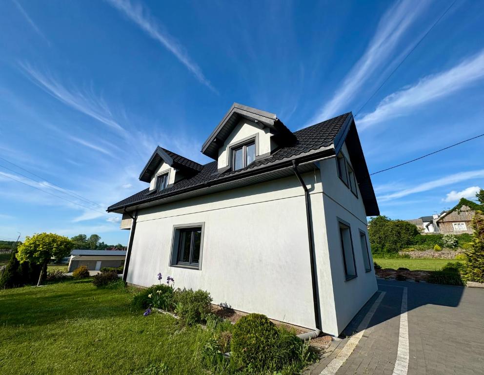 a small white house with a black roof at Biebrzańska Dolina 1 in Goniadz