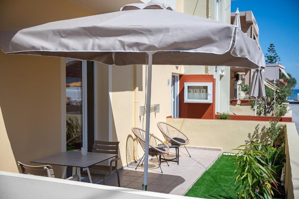 a table and chairs under an umbrella on a patio at Rosmaris Apartments in Platanias