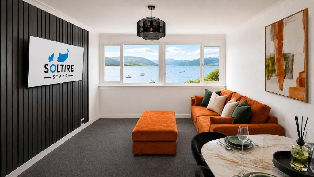 a living room with a couch and a window at Bayview at the Port in Port Bannatyne
