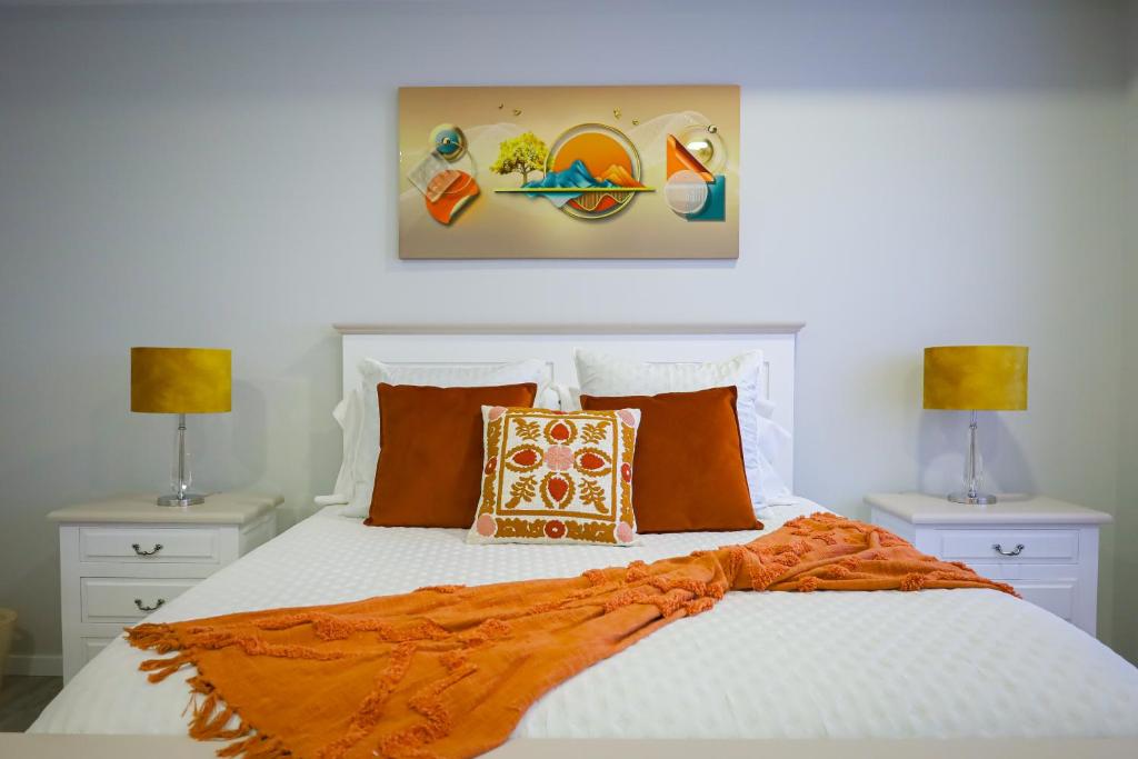 a bedroom with a bed with orange sheets and two lamps at Dreamscape Villa in Ponta Delgada