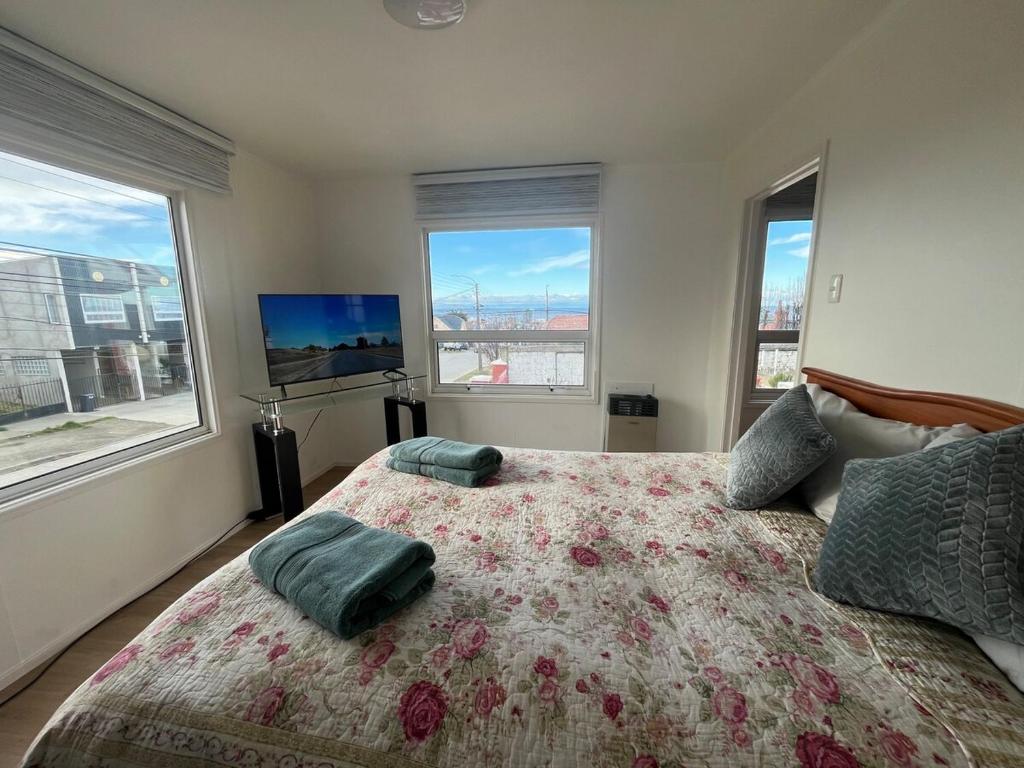 a bedroom with a large bed with two windows at La Casita Austral in Punta Arenas