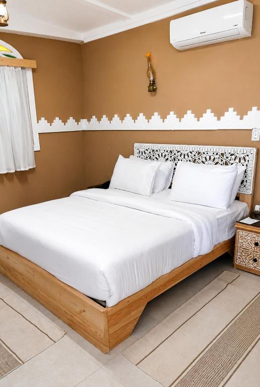 a bedroom with a large bed with white pillows at Happy Oasis Hotel in Siwa